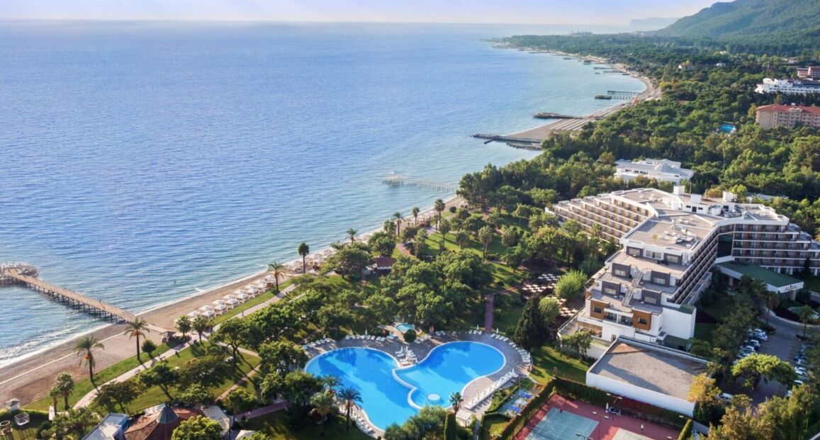 Hotel TUI MAGIC LIFE Beldibi u pláže s horským pozadím.