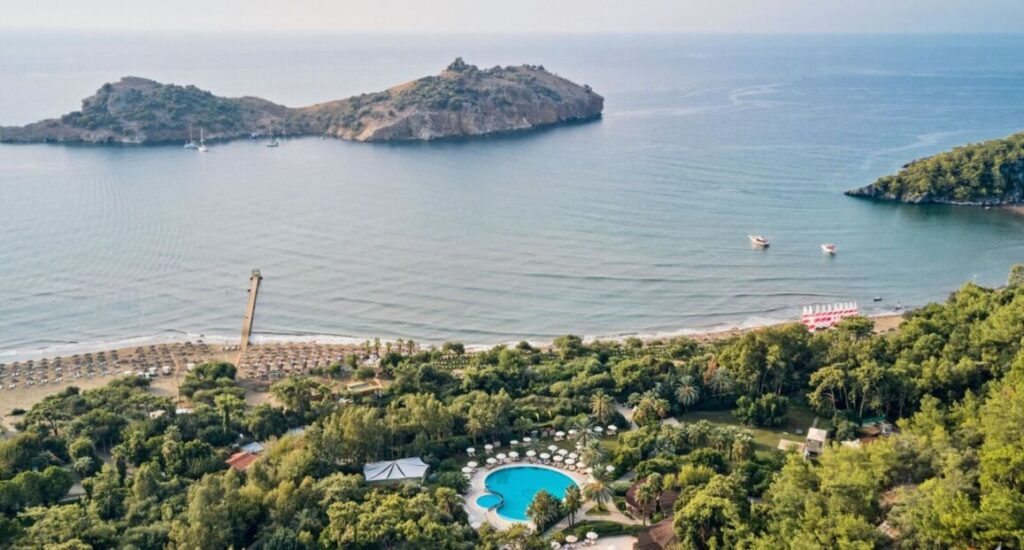 Resort TUI MAGIC LIFE Sarigerme obklopený zelení a s výhledem na moře.