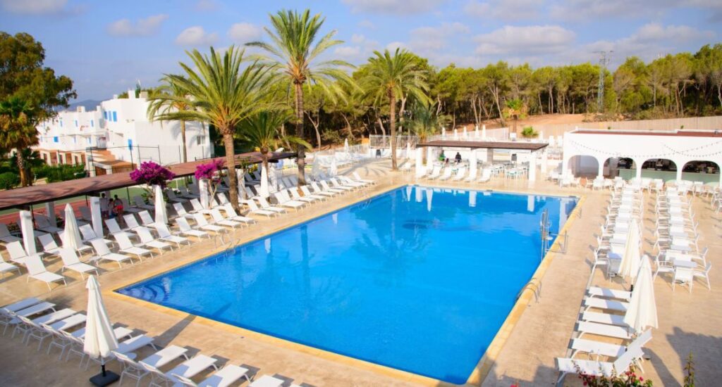 Cala Llenya Resort na Ibize s krásnou pláží a modrou vodou.